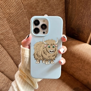 Close-up of baby blue iPhone case with cartoon highland cow art held against a brown fabric