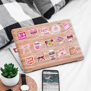Dettaglio di adesivi rosa impermeabili sul laptop con motivi romantici di cuori e libri