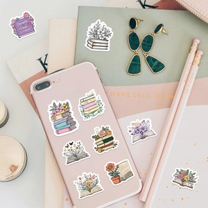 Close-up of floral book stickers on a pink phone case and green notebook cover
