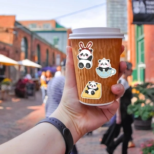Vista detallada de lindas pegatinas de panda aplicadas en una taza de café naranja vibrante