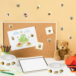 Close-up of cute cartoon bee stickers on paper with teddy bear and color pencils