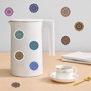 Detail of colorful mandala pattern stickers applied on a white electric kettle and wood table