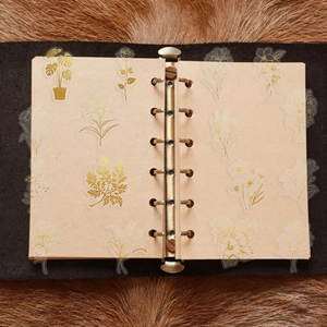Detailed view of gold foil floral stickers on a vintage notebook with PET material