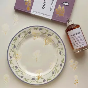 Top view of ceramic dinner plate with purple floral pattern and elegant book decor