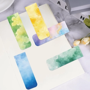 Detailed view of five watercolor magnetic bookmarks on a white notebook with dried flowers