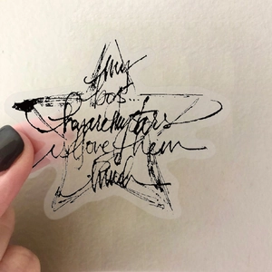 Hand hält einen sternförmigen transparenten Vintage-Ticketaufkleber mit schwarzer Handschrift