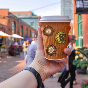 Macro shot of celestial stickers with sun and moon designs on a paper coffee cup