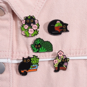 Set of five cute black cat enamel pins featuring plants and flowers on pink denim