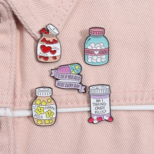 Set of 5 medical enamel pins with pills and bottles designs on pink denim fabric