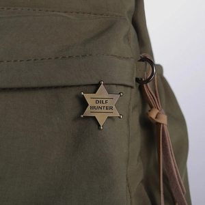 Army green nylon backpack featuring vintage gold star badge with DILF HUNTER engraving