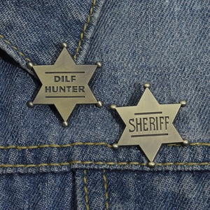Macro shot of vintage metal hexagonal star badges with DILF HUNTER engraving on denim
