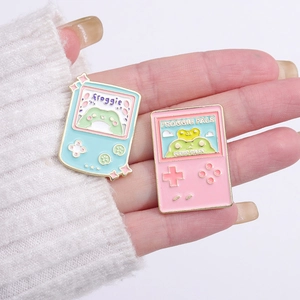 Cute pink and blue retro handheld game console enamel pins featuring cartoon frogs