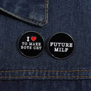 Detail of round black enamel pins with funny text on blue denim fabric background