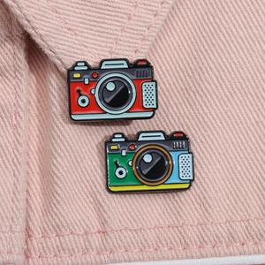 Detailed retro camera enamel pin attached to pink denim fabric collar accessory