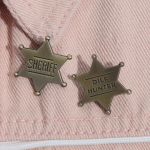 Close-up of vintage bronze star badges with Sheriff engraving on pink denim fabric