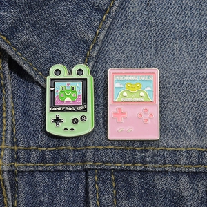 Close-up of retro game console pins with frog theme on dark blue denim fabric