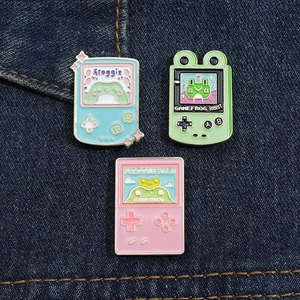 Close-up of retro game console enamel pins with frog theme on blue denim fabric