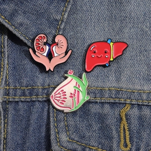 Detailansicht kreativer Emaille-Anstecknadeln mit Organ-Motiven auf einer Jeansjacke