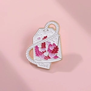 Detalle de broche esmaltado con forma de sobre de té, motivos de corazón y LOVE