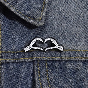 Detail der Skeletthände-Herz-Emaille-Anstecknadel auf Jeansjacke für Halloween