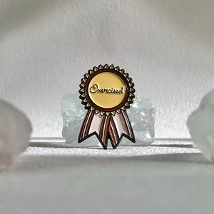 Détail de la broche en émail en forme de médaille avec texte Exercised sur pierre