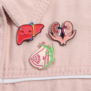 Detailaufnahme kreativer Emaille-Pins mit medizinischen Organen auf rosa Denim