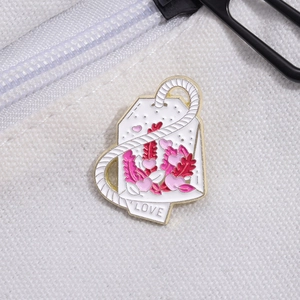 Detalle macro del broche de esmalte con forma de bolsa de té y etiqueta LOVE en lona