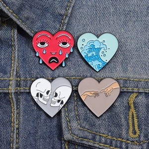 Dettaglio di quattro spille in smalto a forma di cuore con onde e teschio su denim