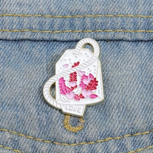 Detalle de broche esmaltado con diseño floral y texto Love sobre tela denim
