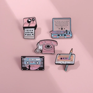 Detail of pink vintage enamel pins featuring retro camera and vinyl record player