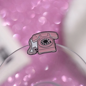 Detail view of a pink retro rotary phone enamel pin with a polished alloy finish