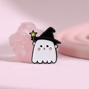 Détail du pin's fantôme blanc avec chapeau de sorcière sur un fond rose texturé élégant