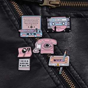 Detailed view of pink vintage enamel pins featuring retro vinyl player and camera icons