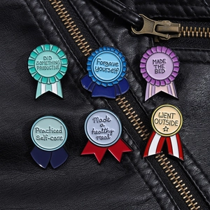 Détail de six épinglettes colorées en émail en forme de médaille sur fond de cuir noir