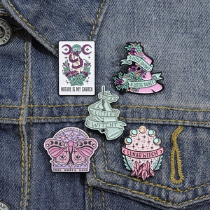 Detailed close-up of five colorful enamel pins including witch hat and crystal ball on denim