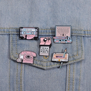 Set of 5 pink retro enamel pins with radio and camera designs on blue denim jacket