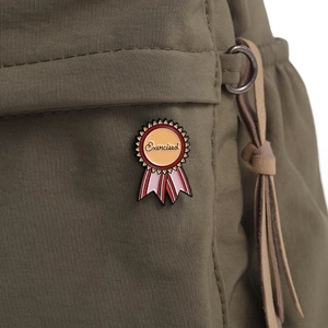 Détail du pin's émaillé 'Exercised' en forme de médaille sur tissu en nylon vert