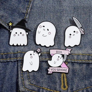 Gros plan de cinq épingles en émail de fantômes mignons sur tissu en jean bleu