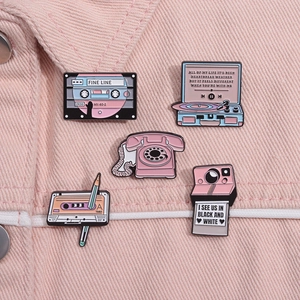 Retro pink enamel pins set featuring cassette tapes and vintage camera on denim fabric