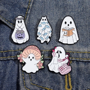 Dettaglio di cinque simpatici spilli in smalto a forma di fantasma su jeans blu