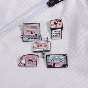 Detail of five retro enamel pins featuring vintage camera, vinyl player, and cassette tapes