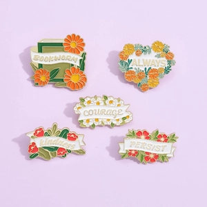 Detailansicht floraler Emaille-Pins mit motivierenden Sprüchen wie Mut und Güte