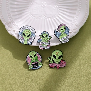 Nahaufnahme von fünf kreativen grünen Emaille-Ansteckern mit lustigen Alien-Motiven