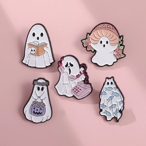 Dettaglio di cinque simpatiche spille in smalto a forma di fantasma su sfondo rosa