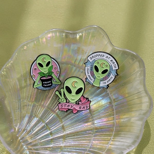 Detailansicht von drei kreativen grünen Alien-Emaille-Pins mit einzigartigen Grafikdesigns