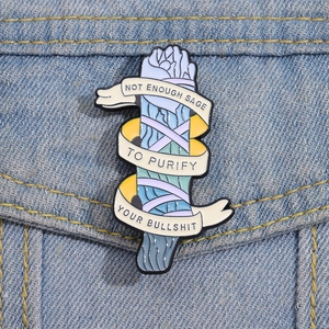 Detailed enamel sage bundle pin on denim jacket with motivational quote typography