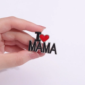 Détail macro de la broche émaillée 'I ❤️ MAMA' avec cœur rouge et bords en métal argenté