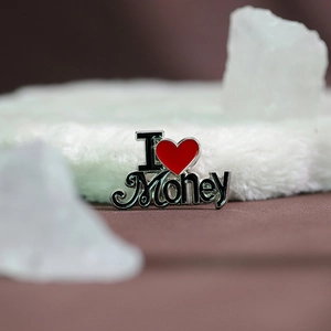 Dettaglio macro della spilla smaltata con scritta I Love Money e cuore rosso acceso