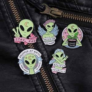 Detailansicht von fünf Alien-Emaille-Pins an einem schwarzen Lederjackenkragen