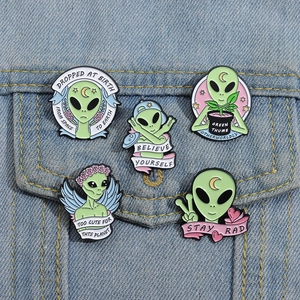 Detailansicht von fünf süßen grünen Alien-Emaille-Pins auf einer blauen Jeansjacke